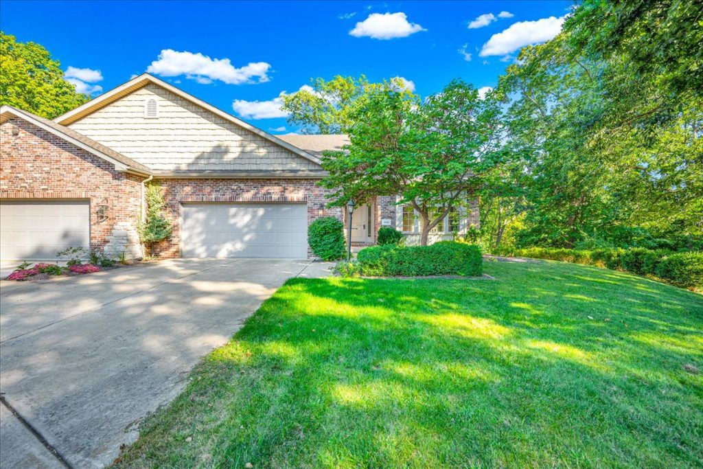 The front of a brick home with two car garage and landscaped yard.